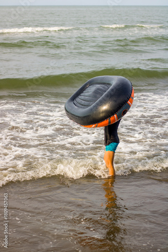 little girl holding a rubber boat on the beach