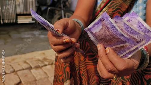 An indian woman counting 100 rupees indian currency notes.