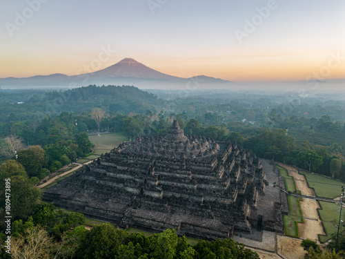 Aerial view of Borobudur Temple in Central Java, Indonesia. Ancient Buddhist monument at sunrise, with Merapi volcano in the background. UNESCO World Heritage Site, culture, history, and travel themes