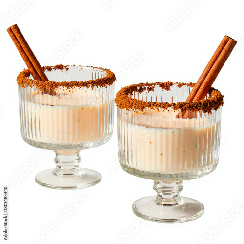 Two festive holiday drinks with cinnamon sticks and rimmed glasses