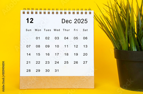 White December 2025 calendar on yellow cover background. Year end concept.