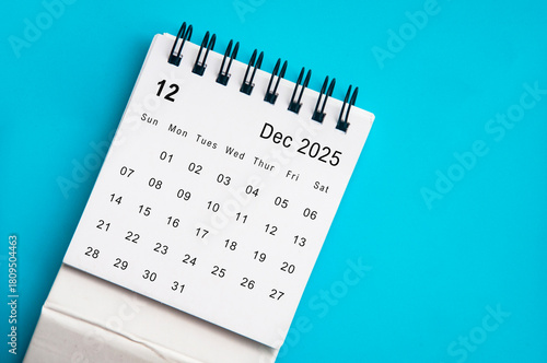 Top view of December 2025 desk calendar on blue cover background. December month and year end concept.