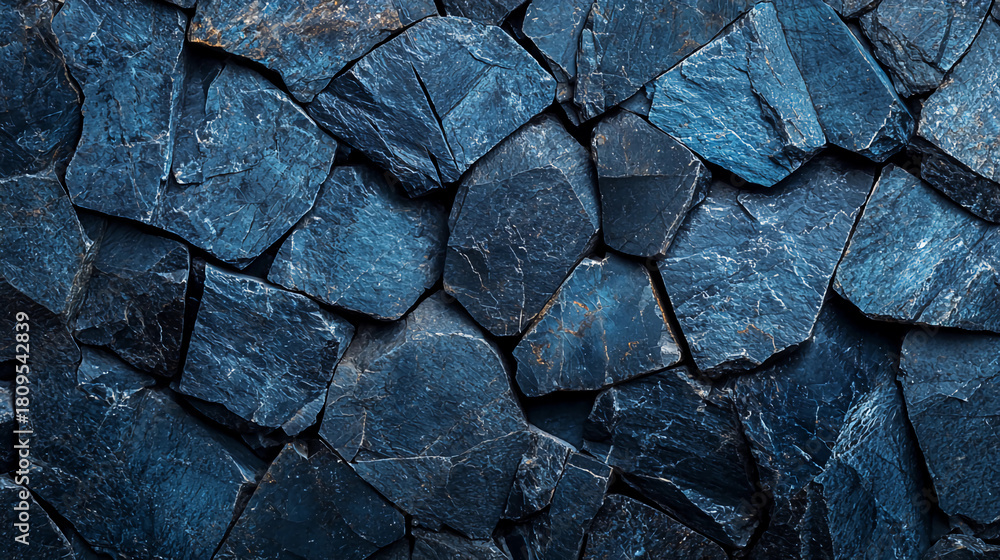 Fototapeta premium A textured surface of dark blue slate stones arranged irregularly, creating a striking pattern that highlights natural geological formations.