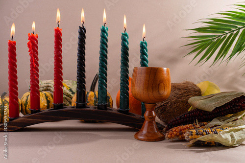 Happy Kwanzaa. Seven candles red, black and green on a natural wooden background. Harvest and gifts. Symbols of African heritage.