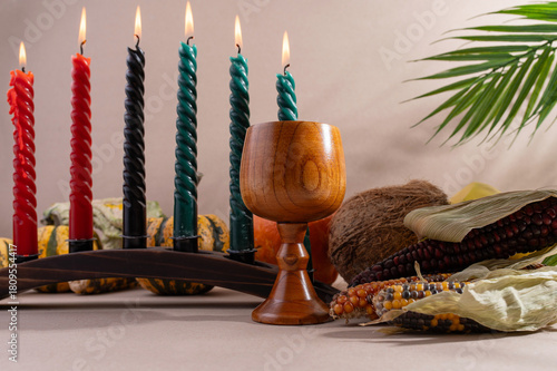 Happy Kwanzaa. Seven candles red, black and green on a natural wooden background. Harvest and gifts. Symbols of African heritage.