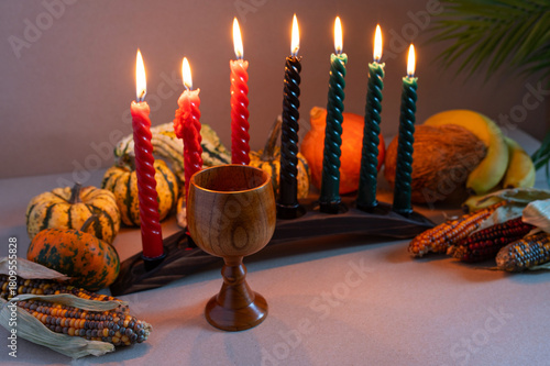 Happy Kwanzaa. Seven candles red, black and green on a natural wooden background. Harvest and gifts. Symbols of African heritage.