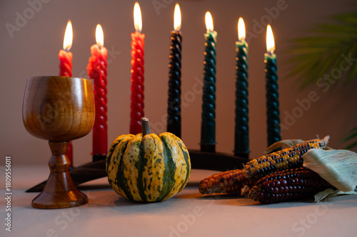 Happy Kwanzaa. Seven candles red, black and green on a natural wooden background. Harvest and gifts. Symbols of African heritage.