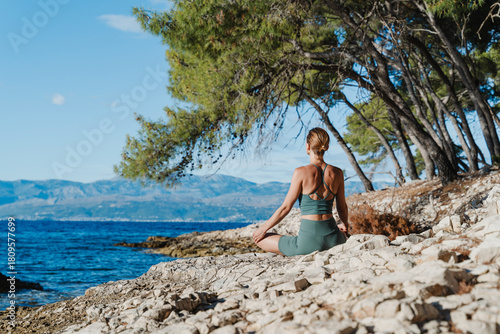 Woman meditating in nature with sea view. Young female practicing yoga in beach. Beautiful woman exercising outdoors and practicing yoga asanas at seaside. Holistic Health and Mental Well-Being.