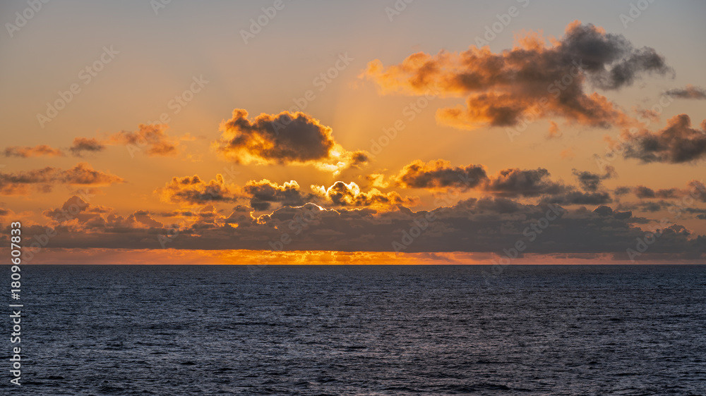 Naklejka premium Ocean Sunset with Clouds and Golden Light