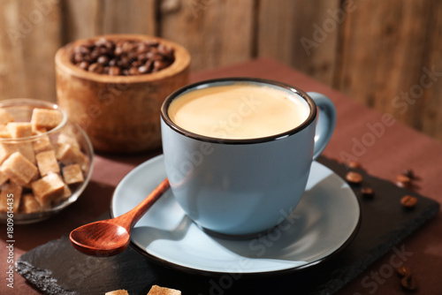 Aromatic coffee in cup, beans and brown sugar on table, closeup