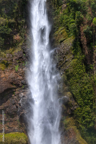 Giant waterfall cascading flow of water surrounded by lush scenery