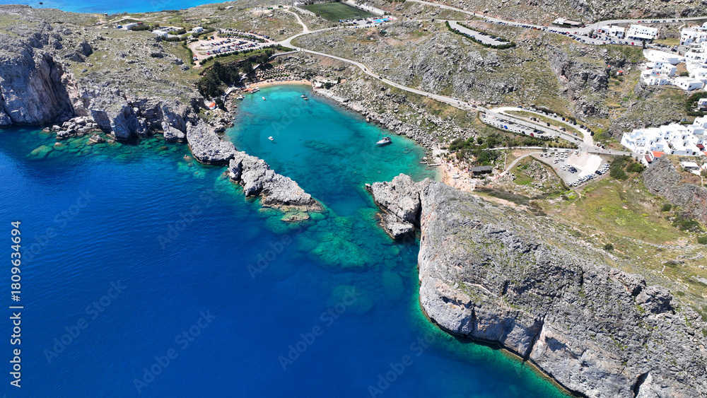 Obraz premium Aerial drone photo of elliptical shaped paradise bay and chapel of Saint Paul, featuring organized beach and crystal clear calm turquoise waters, Rhodes island, Dodecanese, Greece