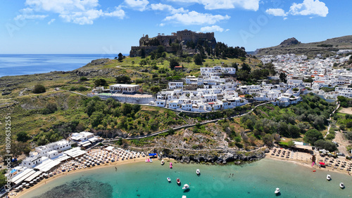 Aerial drone photo of iconic archaeological site of Acropolis of Lindos built uphill featuring picturesque village, amazing organized beach and Saint Paul bay, Rhodes island, Dodecanese, Greece