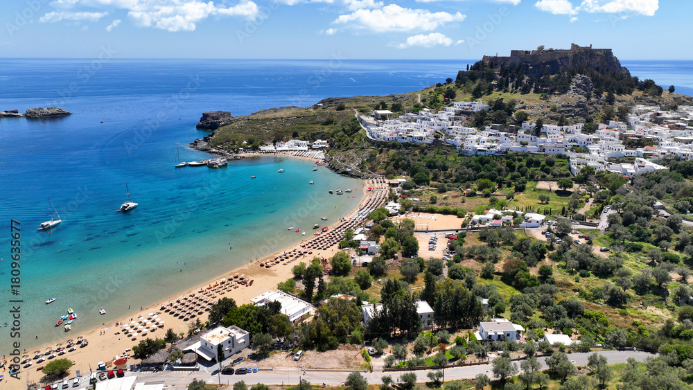 Fototapeta premium Aerial drone photo of iconic archaeological site of Acropolis of Lindos built uphill featuring picturesque village, amazing organized beach and Saint Paul bay, Rhodes island, Dodecanese, Greece