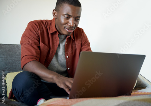 Young African man working remotely from home on a laptop