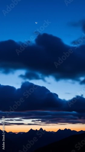 Dramatic evening sky over mountain range with vivid clouds and a crescent moon, a stunning atmospheric video to evoke tranquility and awe