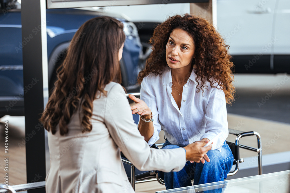 Naklejka premium Two Women Having a Serious Conversation at a Car Dealership Showroom