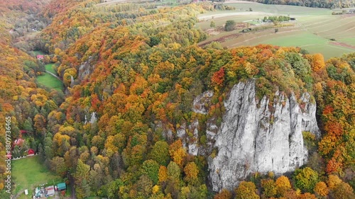 Aerial drone view of Sokolica Rock (Skała Sokolica) in the Polish Jura (Jura Krakowsko-Częstochowska). Limestone cliffs surrounded by vibrant autumn forest.
