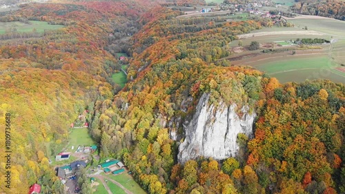Aerial drone view of Sokolica Rock (Skała Sokolica) in the Polish Jura (Jura Krakowsko-Częstochowska). Limestone cliffs surrounded by vibrant autumn forest.