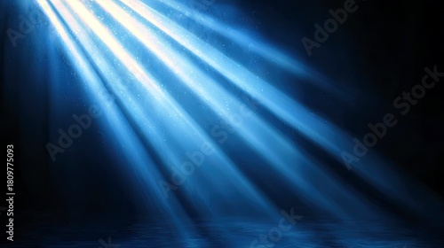 Diagonal beams of bright blue light cut through a dark background, illuminating tiny particles in the air and reflecting on a textured, watery surface below.