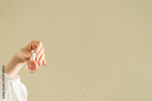woman's hand holding pink nail polish.