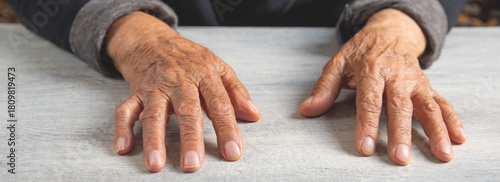 Caucasian elderly female hands on the wooden table.