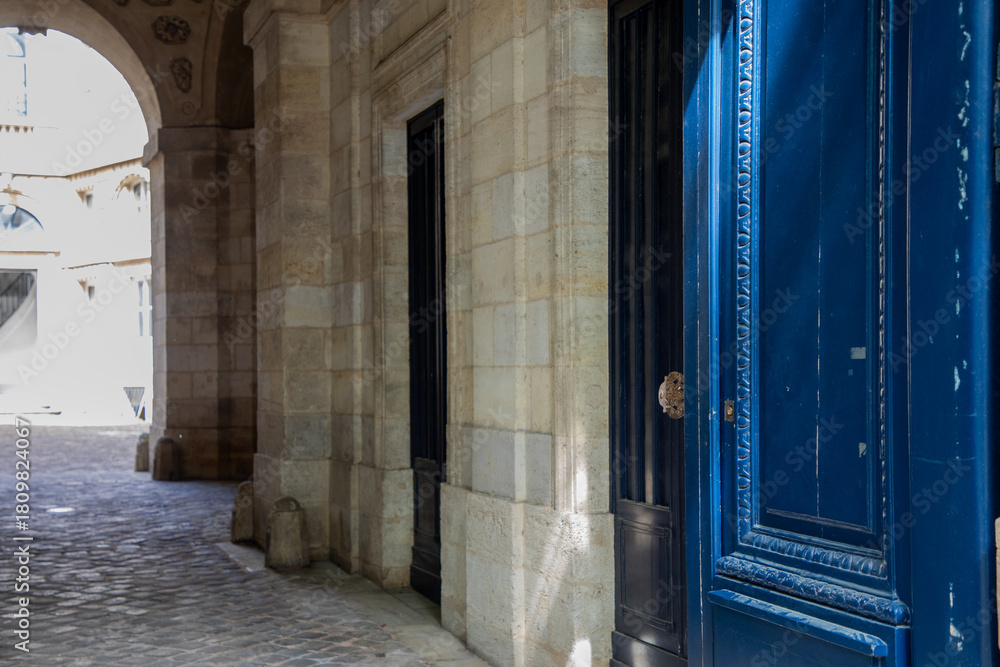 Fototapeta premium wooden vibrant blue door and stone archway in french european courtyard in the old town