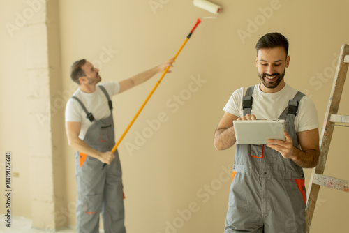 Two workers painting a wall...