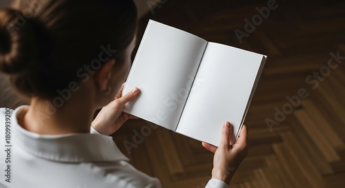 Fototapeta Naklejka Na Ścianę i Meble -  Overhead shot of a person holding an open blank book or magazine with empty pages, ready for text or images, indoors
