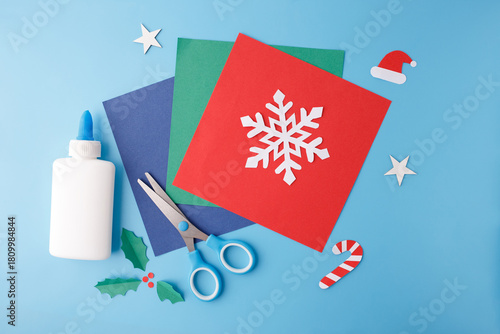 Holiday craft flat lay with paper snowflake, scissors, glue, festive cutouts. Perfect for DIY blogs, kids activities, stationery brands, seasonal marketing, education platforms