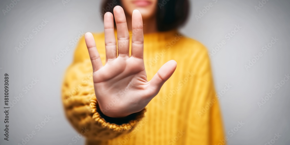 Obraz premium Woman extends hand in stop gesture, signaling refusal, restriction, and personal boundaries. Cropped close up, neutral background