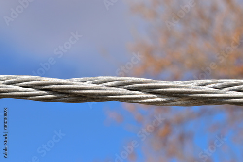 Canvas Print Twisted steel cable with cloudy sky background.