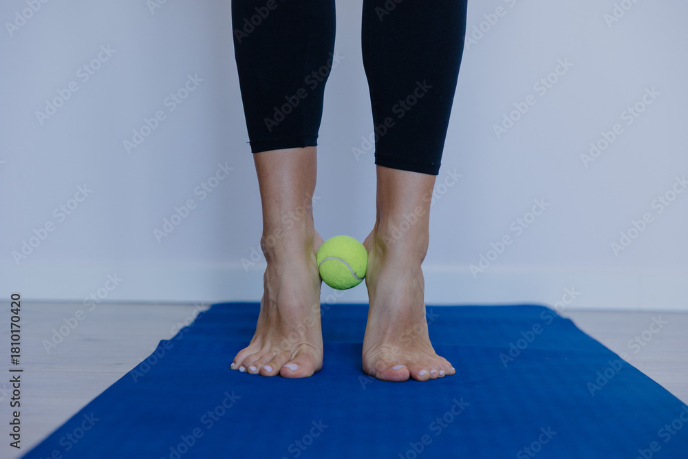 Naklejka premium Close-up of feet, Woman doing foot gymnastics with tennis ball on yoga mat