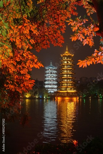 Die Sun and Moon Pagoda erleuchten in der Dunkelheit und spiegeln sich im Wasser. Umgeben von der Herbstfärbung der Bäume.
