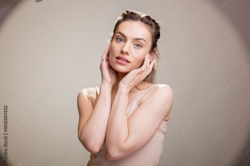 Obraz premium Female model posing with confidence for a cosmetics advertisement, wearing radiant natural makeup in the studio. Graceful positive expression embracing self acceptance and femininity.