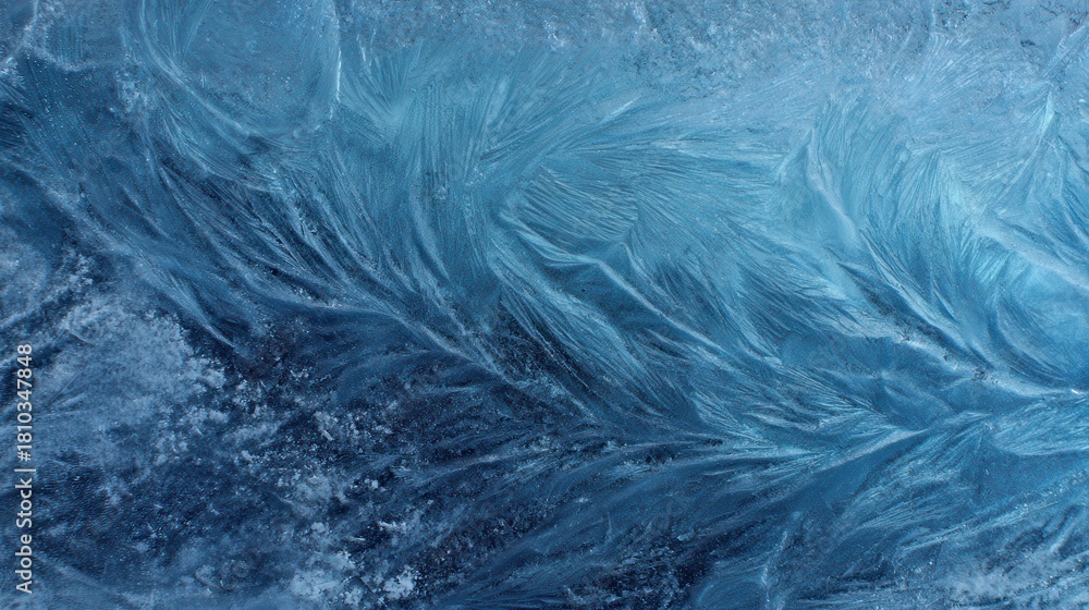 Fototapeta premium Intricate patterns of frost crystals forming delicate feathery shapes on a blue icy surface