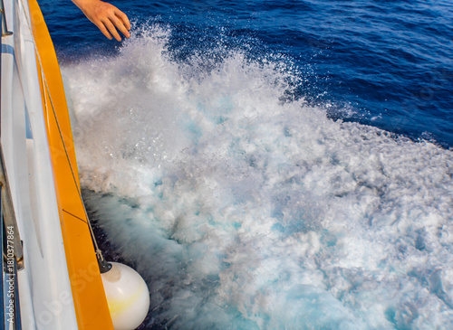 Fototapeta Naklejka Na Ścianę i Meble -  Ship foam and a white boat fender, human hand, sea background