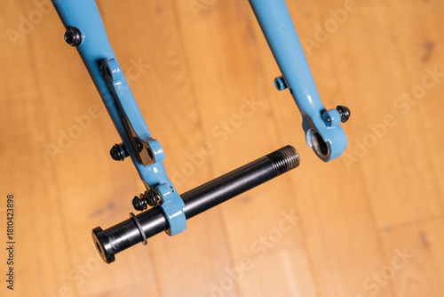 Close up of a bicycle frame rear dropout showing a partially inserted thru-axle and disc brake mount.