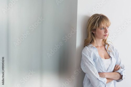 Woman mid-20s leaning on white wall by frosted glass, wearing shirt, looking right, copy space Free Download Woman mid-20s leaning on white wall by frosted glass, wearing shirt, looking right, copy space - GFXLoad