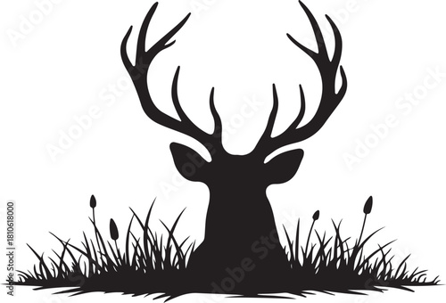Black silhouette of a deer head with antlers in grass