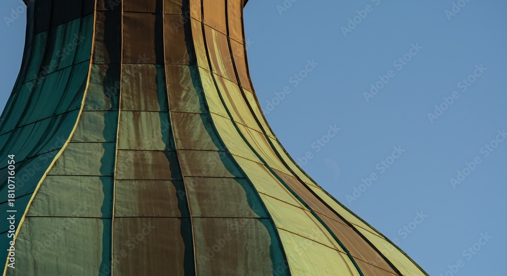 Obraz premium A closeup captures the curved aged copperpaneled roof of a building against a clear blue sky