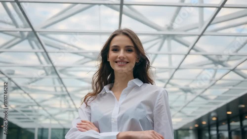 Young woman smiling confidently under a modern geometric glass structure with natural light