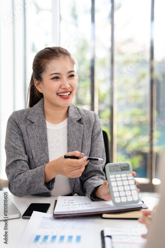 Smiling asian businesswomen financial advisor explaining financial result showing calculator to client or Collegue  in meeting.