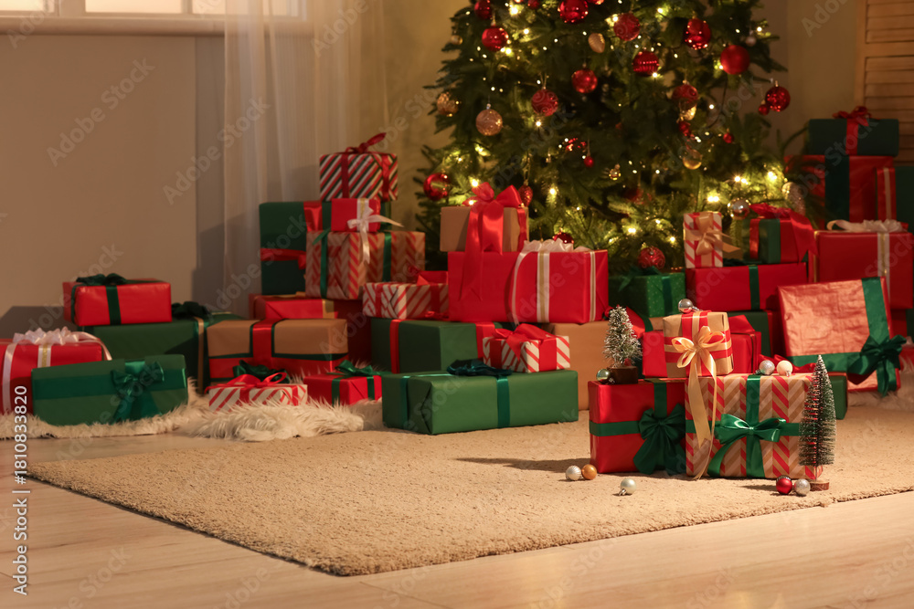 Obraz premium Many different gift boxes with decorations near Christmas tree in festive room at night