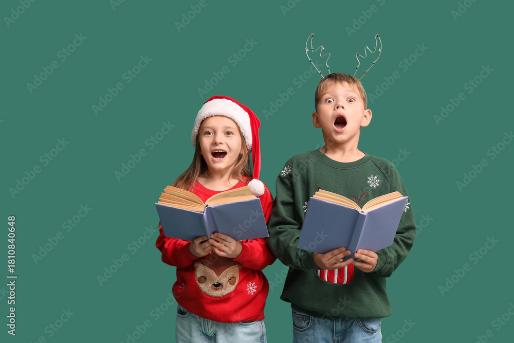 Naklejka premium Surprised little children reading Christmas story on green background