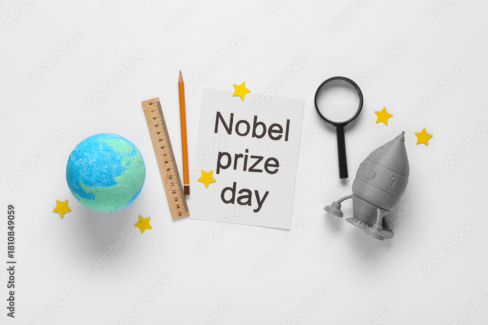 Fototapeta premium Paper with text NOBEL PRIZE DAY, earth model, rocket and stationery on white background