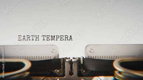 Old mechanical typewriter typing Earth Temperature in a close-up view, with metal letters striking the white paper.