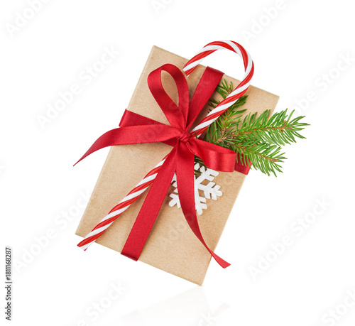Christmas gift box wrapped in craft paper decorated with candy red cane in white stripes and fir branches with snow isolated on white background with clipping path. Design element