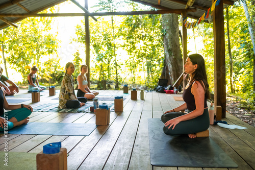 Yoga instructor leading seated meditation outdoors.