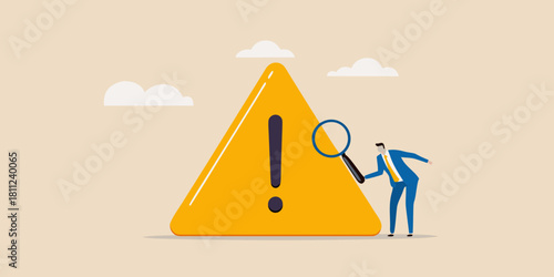 Businessman inspecting a warning sign with a magnifying glass for risks